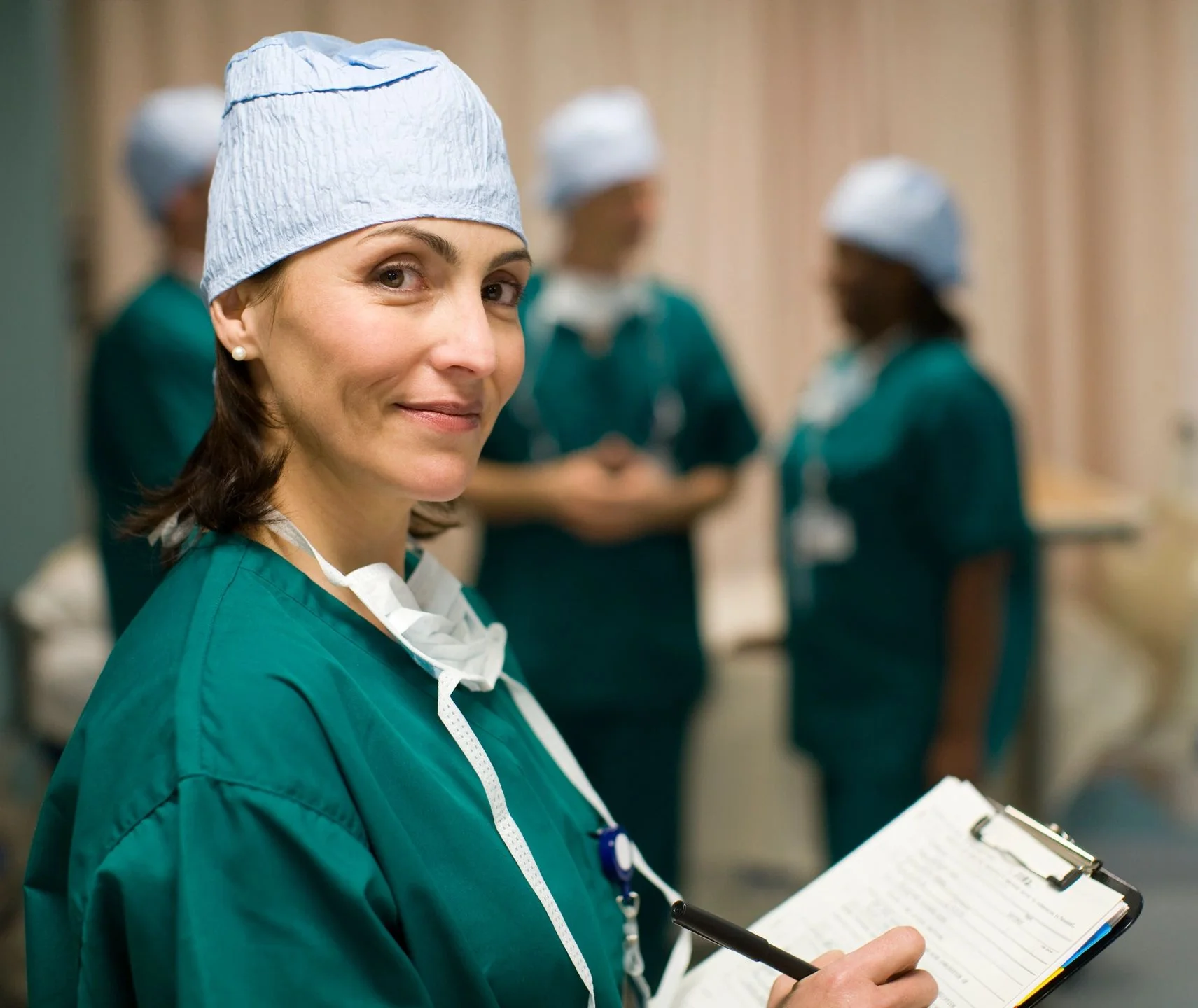 Clinician in teal scrubs holding a clipboard, from the official Fistula Solution website